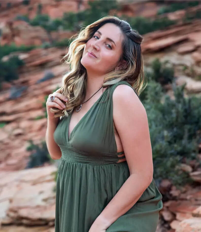 A woman wearing a green dress poses in a desert landscape.